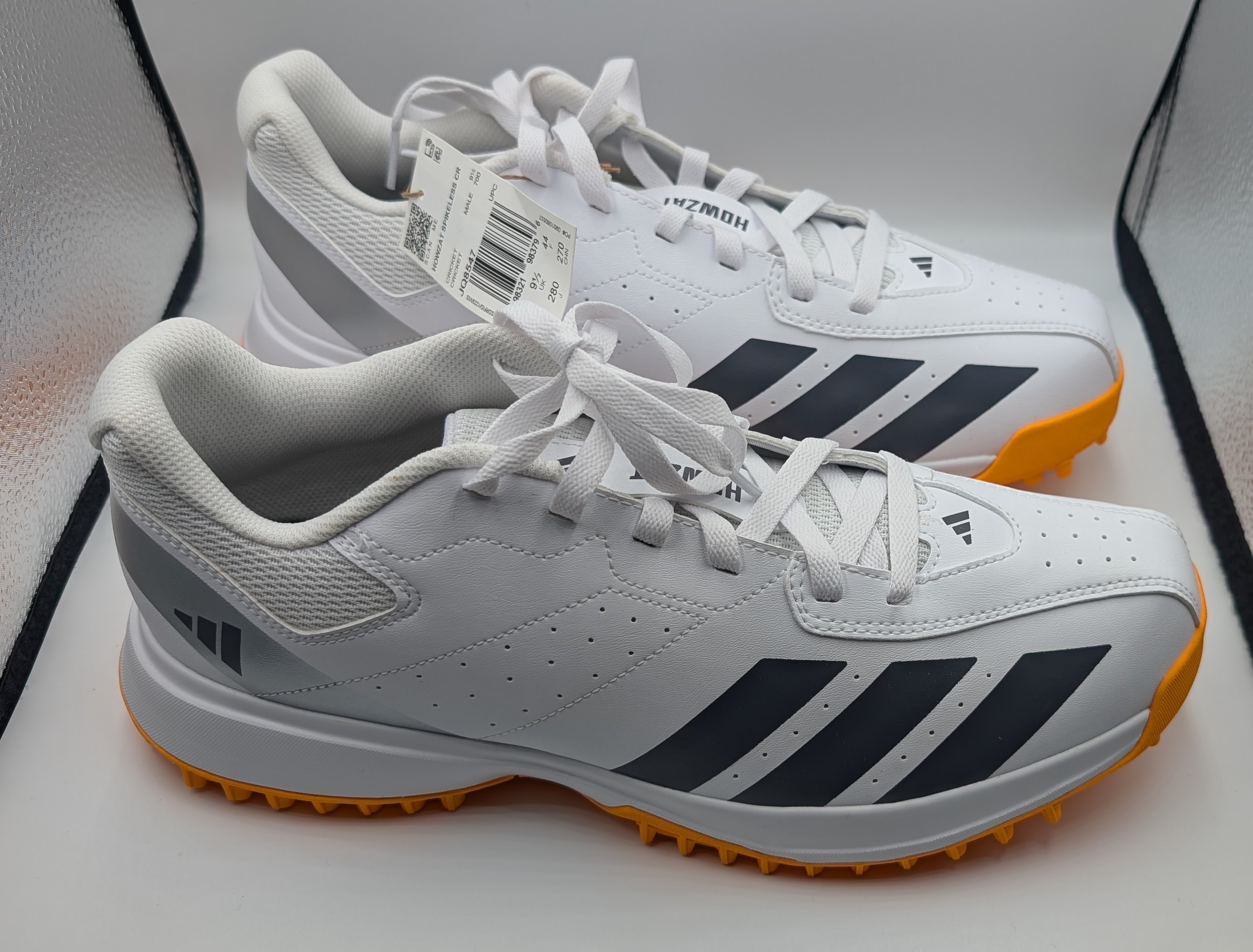 Spikeless Cricket shoe pair with Adidas logo and orange sole