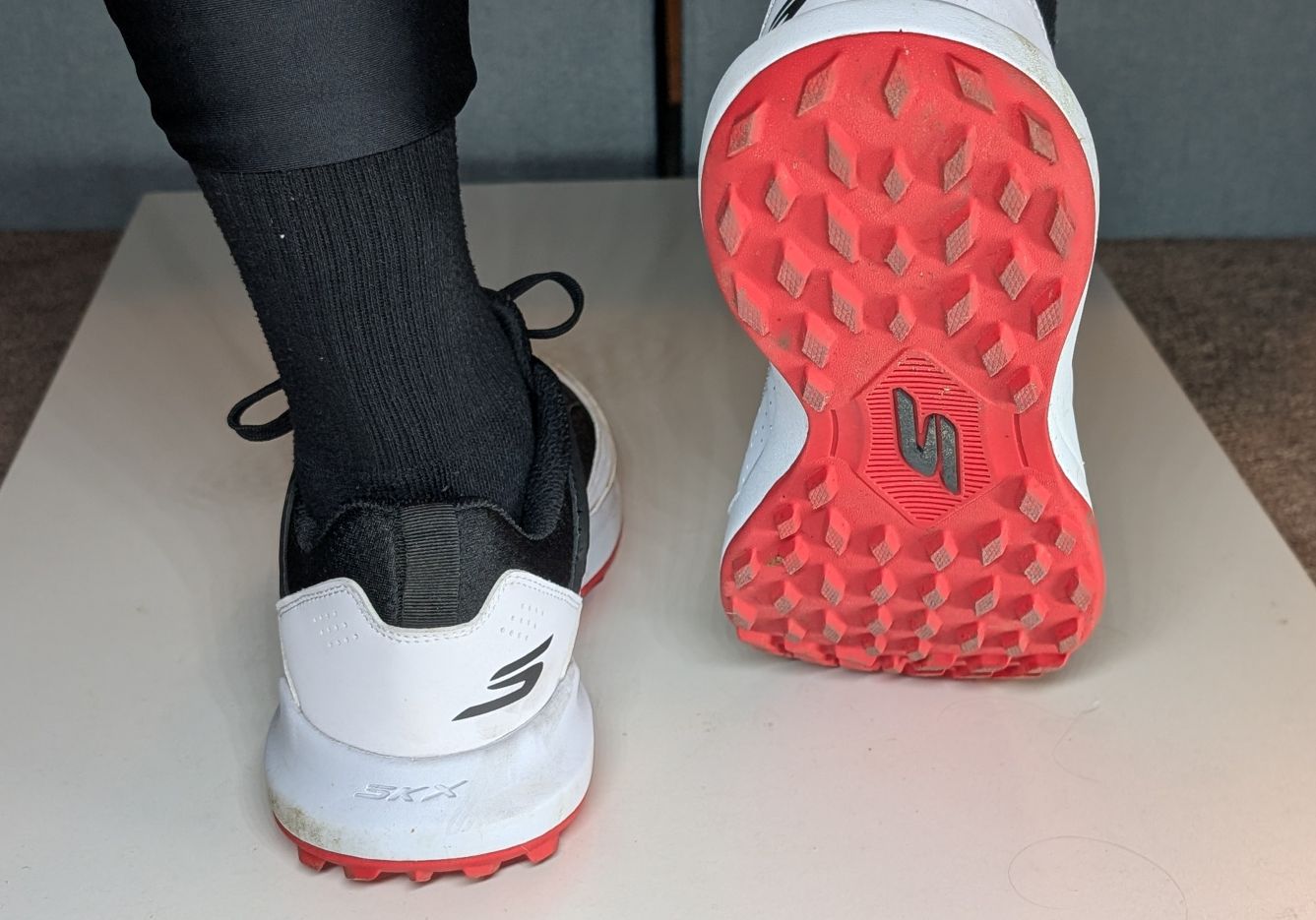 Red outsole of Skechers turf cricket shoes on feet