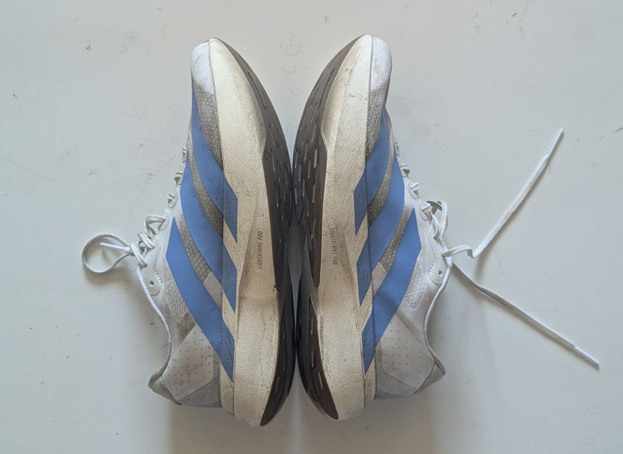 Two adidas running shoes laid sole to sole with blue logo and LIghtstrike Pro label on midsoles