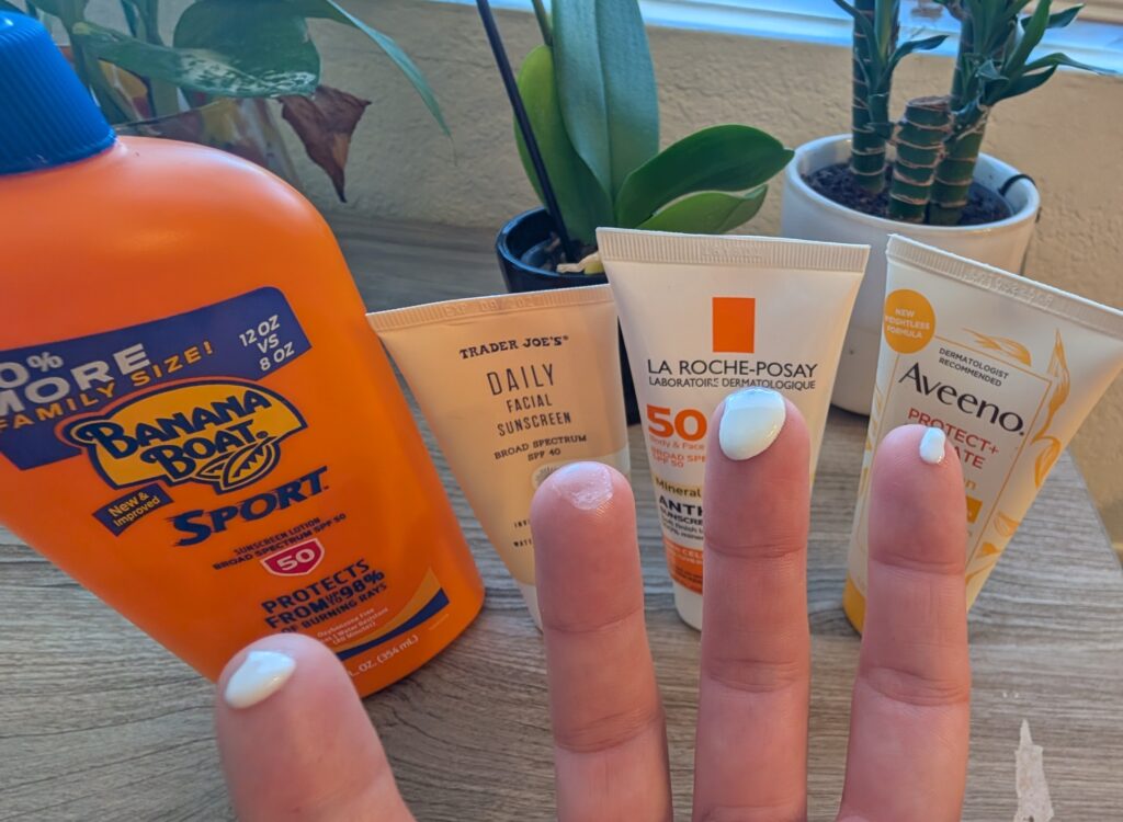 Four sunscreens lined up and lotion texture shown on hands, including Aveeno Protect and Hydrate Sunscreen, Banana Boat, La Roche-Posay, and Trader Joe's Face sunscreen.