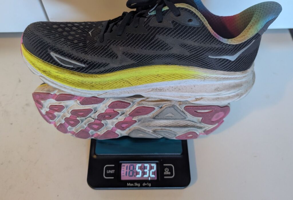 Hoka Clifton 9 black and rainbow running shoes weighed on scale showing 532 grams