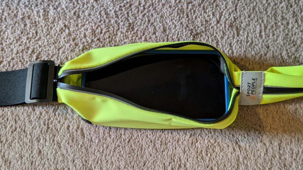 iPhone 12 Pro cell phone in silicone case in larger pocket of Sport2People fluorescent running belt