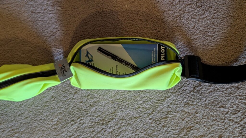 Box of pens inside Sport2People running belt phone pocket to show storage size