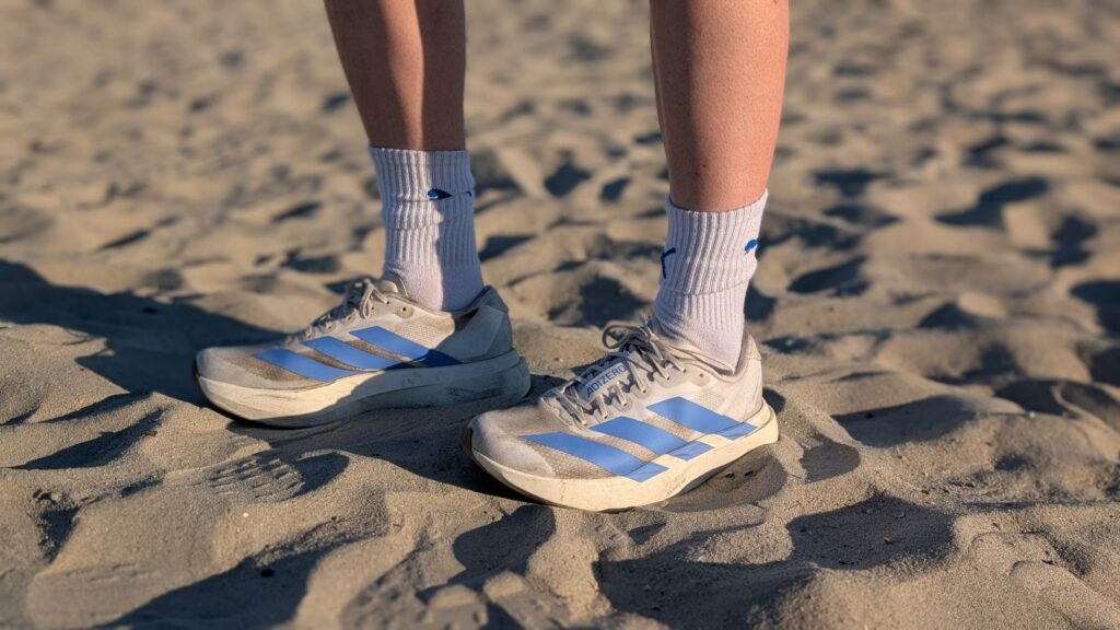 Our Three Cents Reviewer Hannah wearing fusion blue and white Adidas Adizero EVO SL Running Shoes in the sand
