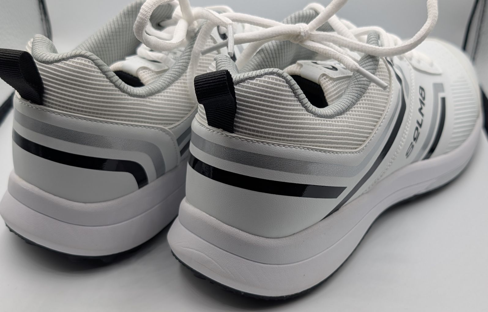 Close up of stitching on SOLM8 s1 rubber spikes cricket shoe in black and white