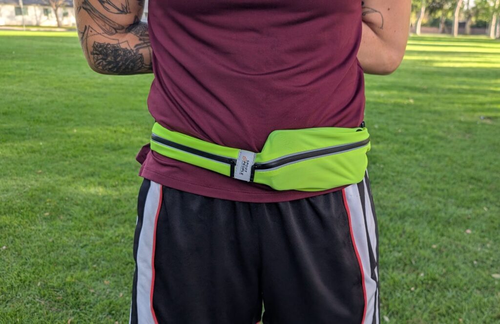 Our Three Cents reviewer in red shirt wearing bright yellow Sport2People running belt around waist with phone in pocket