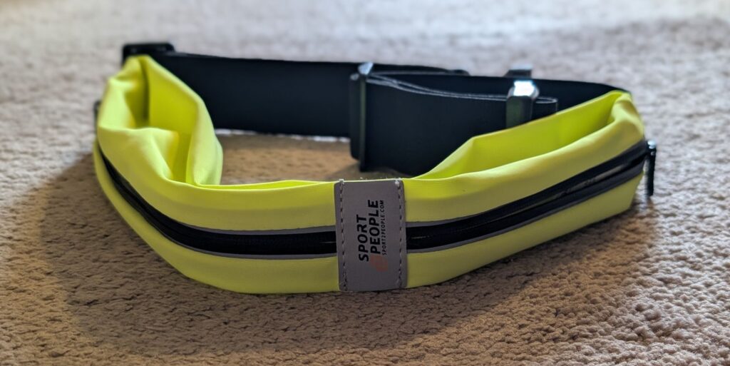 Portrait of Sport2People running belt waist pack in fluorescent yellow on floor