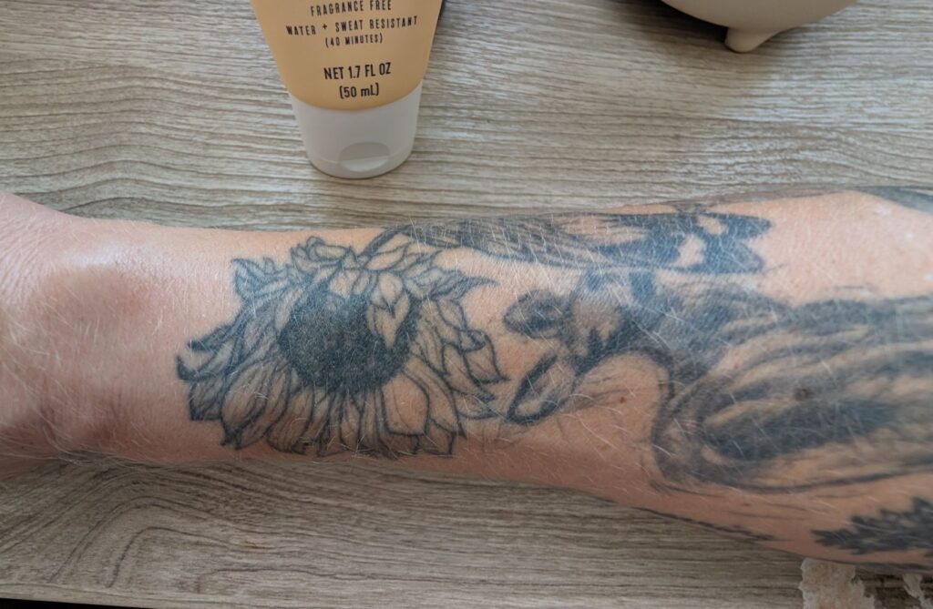 Trader Joe's Daily Facial Sunscreen applied to sunflower tattoo on arm.