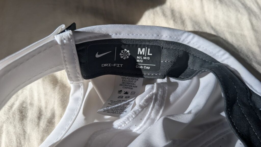 Close up of Nike Dri-FIT Club Unstructured Featherlight Cap M/L size label and care instructions