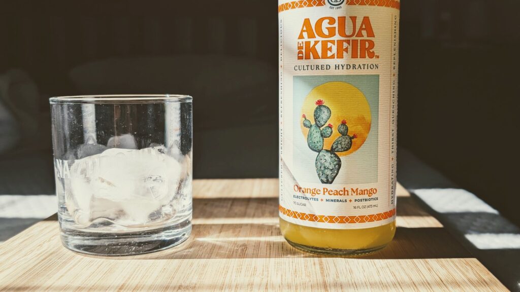 GTs Agua De Kefir Drink Orange Peach Mango Bottle Label and Glass of Ice