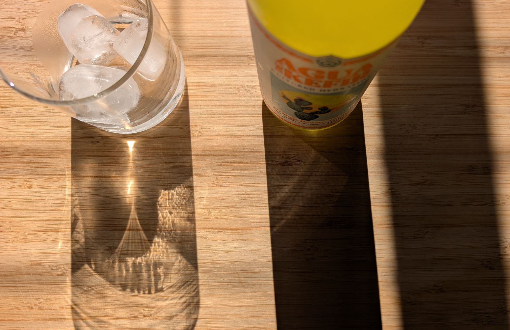 Bottle of GT's Agua de Kefir Orange Peach Mango drink beside a glass of ice for a beverage review