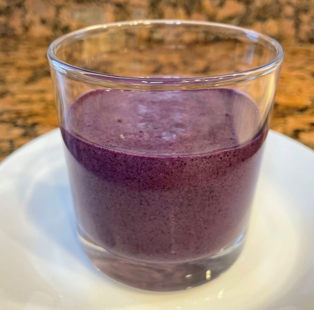 Purple high protein smoothie recipe poured in a clear glass