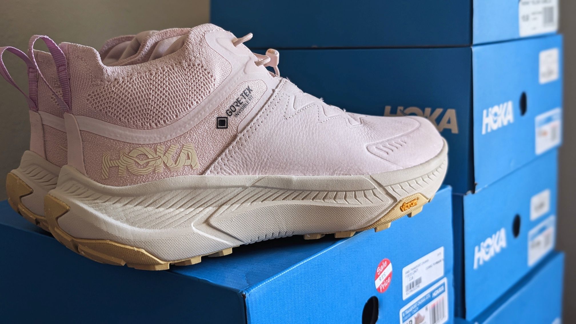 Pink Transport Chukka shoe on stack of blue boxes to show where to buy Hoka shoes on sale