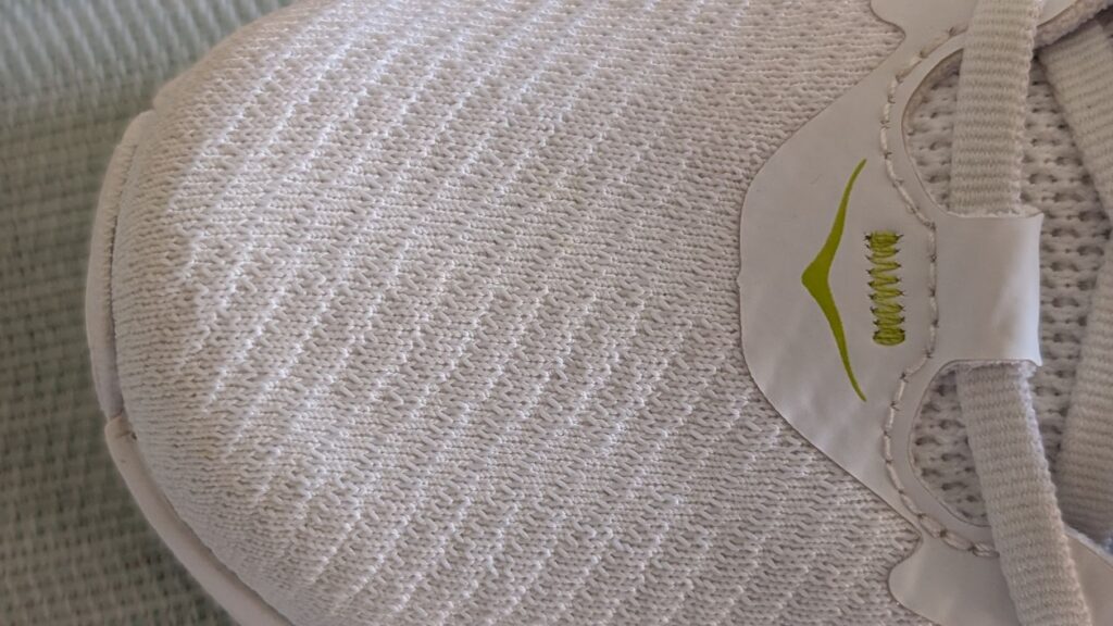 Detailed view of stretchy shoe upper with green Hoka logo