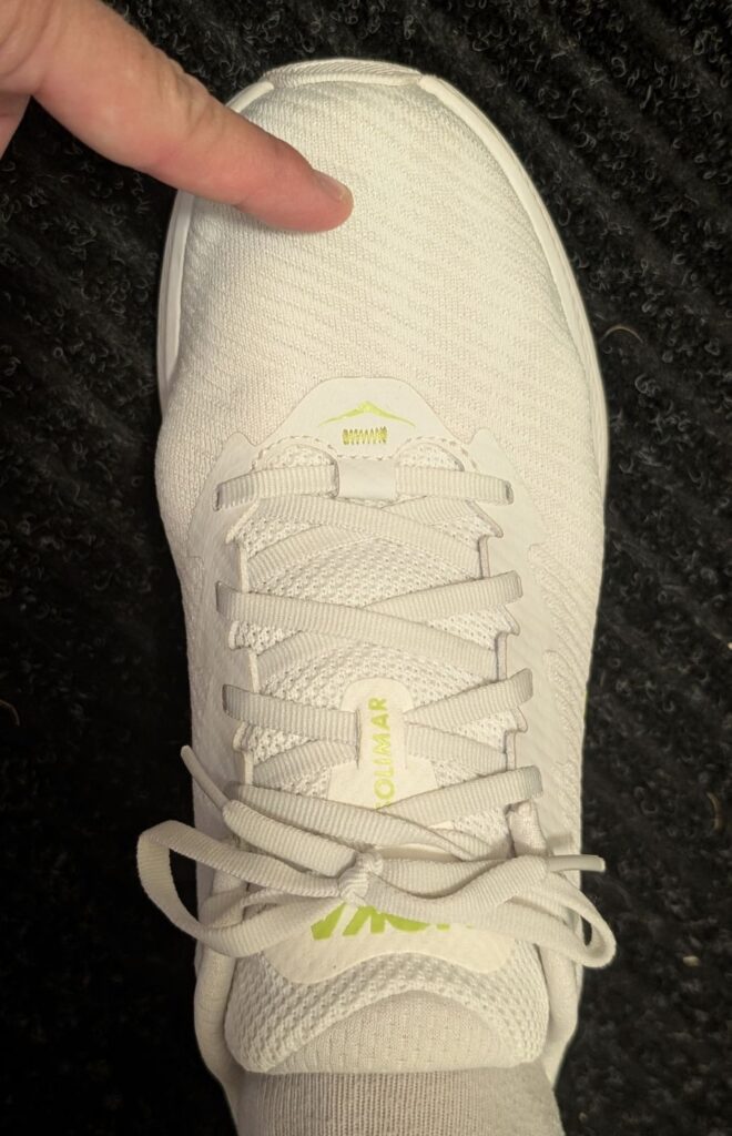 Finger pointing to toe to show length on Solimar 10D shoe in white