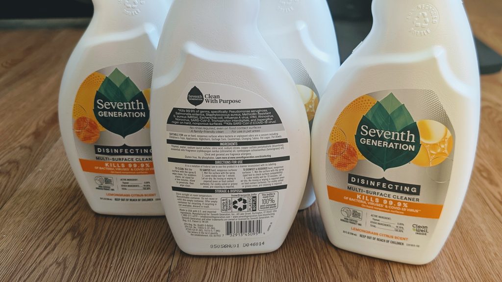 Seventh Generation plant-based disinfectant spray bottles set on a wood floor
