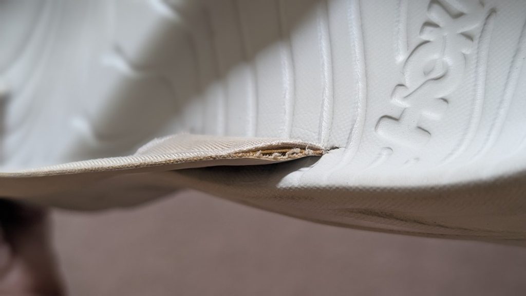 Close up of peeling strap on Hoka flip flop.