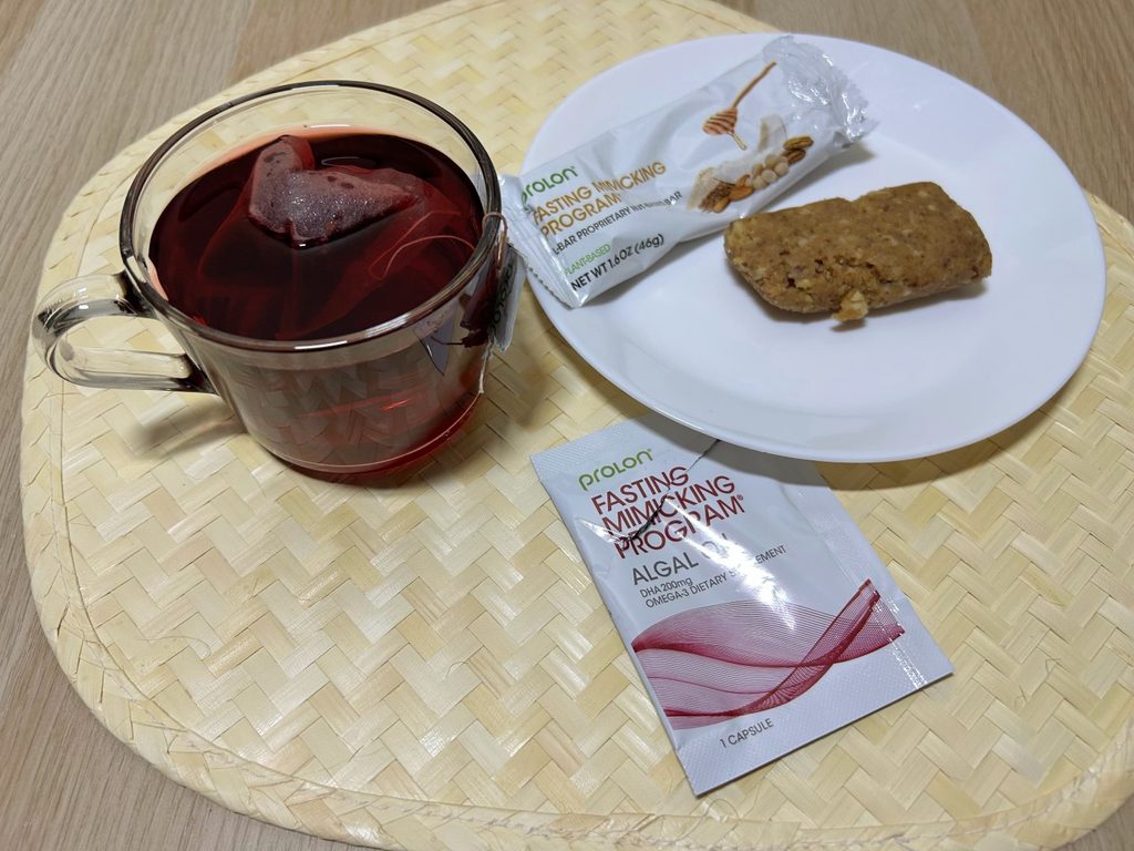 Red tea, fasting mimicking program bar, and agal capsule from Prolon on placemat